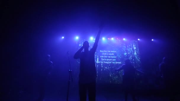 Blaulicht. ein Mann mit erhobener Hand, der auf der Bühne singt. eine Musikgruppe bei einem Konzert. Verschwommene Sicht — Stockvideo