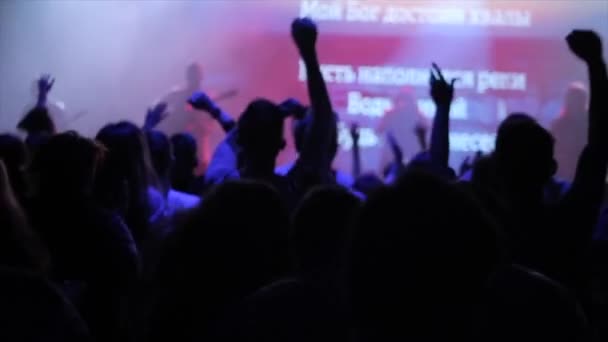 Beaucoup de jeunes sautent à un concert. Certaines mains sont levées. Vue arrière. Lumière bleue . — Video