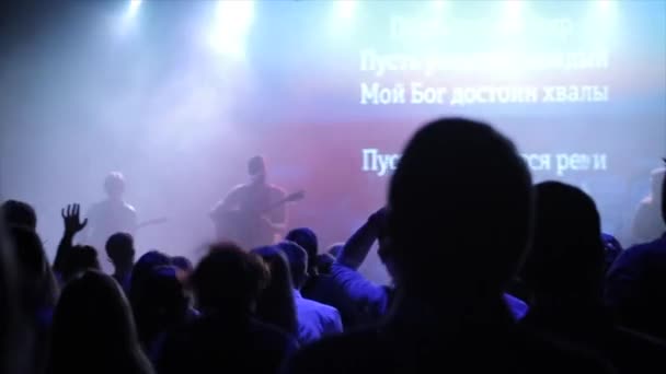Young people enjoying the concert. Some of them jump, some stand. Cheering. Blue light. Back view — Stock Video