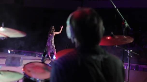 Bobruisk,Belarus - JULY 31, 2018: Rock concert. A nicely dressed pretty woman singing on stage. A male drummer playing the drums on the background. Rear view — Stock Video