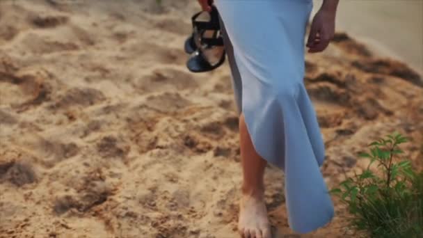 Krásná žena nosí chůze naboso na pláži, večerní šaty držení boty. Zpomalený pohyb. Nohy do písku — Stock video