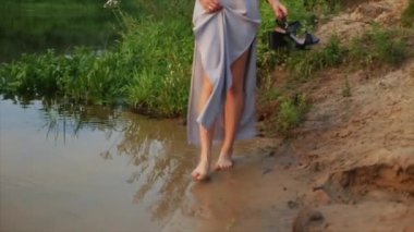 Arkadan görünüm üç ince kız çıplak ayakla sahilde akşamları çalışan. Ağır çekim. Göl. Ayaklar görünümü.