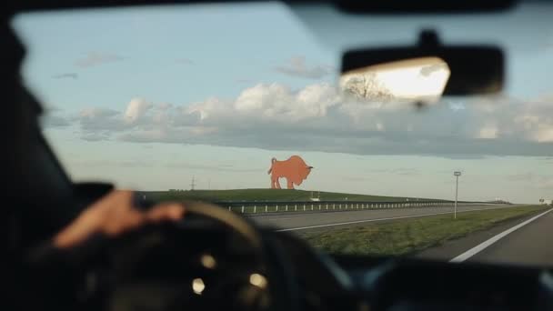 Köra förbi ett monument av en buffel på vitryska motorväg med vacker himmel i bakgrunden — Stockvideo