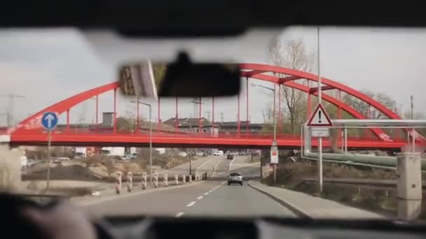 Sie fahren unter einer roten Brücke eine Landstraße hinunter. eine Weggabelung — Stockvideo