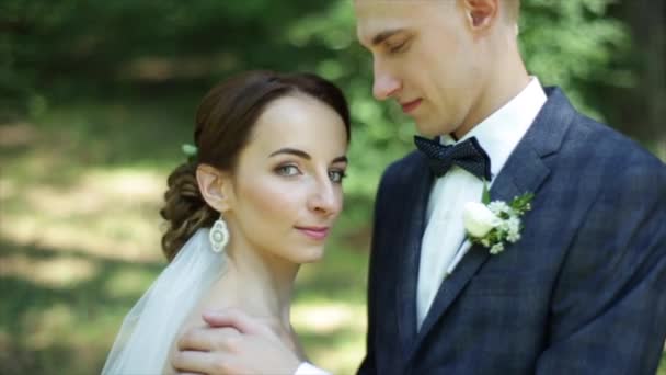 A bride putting head on grooms shoulder. Slow motion. A close-up. A beautiful just married couple. Wedding photo shooting. Look at the camera. — Stock Video