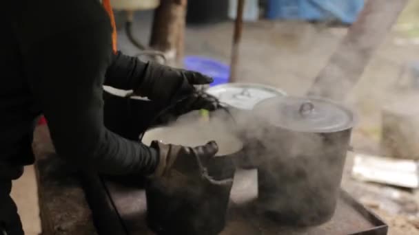 Ein Mann gießt heißes Wasser in einen altmodischen Eimer. — Stockvideo