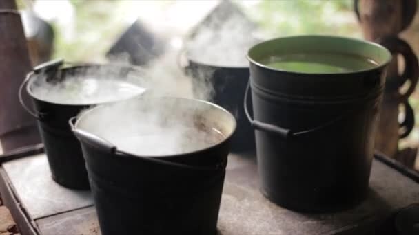 Water opwarmen in de oude ouderwetse emmers. — Stockvideo