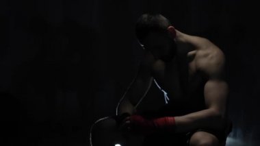 Koyu arka planı kafasıyla oturarak bir üzgün kaslı erkek boxer. Üstsüz bir güçlü sporcu