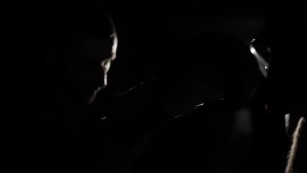 A close-up of a male boxer in boxing gloves practicing punches with a coach. Dark background. Camera light reflection — Stock Video