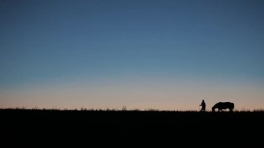 Bir binici atı gün batımında yürüyüş gölgeler