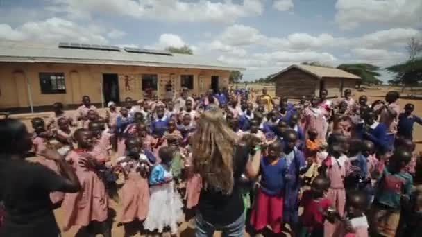 Kenia, Kisumu - 20 mei 2017: Afrikaanse kinderen en Kaukasische vrouwen dansen buiten in lokale school. — Stockvideo