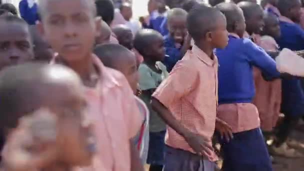 KENYA, KISUMU - 20 MAI 2017 : Des enfants africains en uniforme dansent avec des femmes et des hommes caucasiens à l'extérieur de l'école . — Video