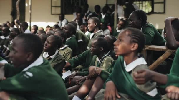 KENYA, KISUMU - MAY 20, 2017: African children in uniform sitting on ground, listen and starting laughing. — Stock Video