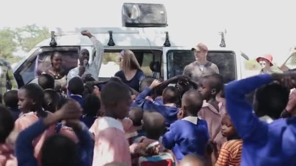 Kenia, Kisumu - 20 mei 2017: Afrikaanse kinderen in uniform tijd doorbrengen met blanke vrouwen en man buiten. — Stockvideo
