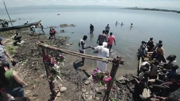 KENYA, KISUMU - 20 MAGGIO 2017: Gli africani entrano in acqua vestiti, celebrando il battesimo nel lago . — Video Stock