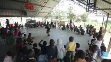 Kenya, Kisumu - 20 Mayıs 2017: çemberin içinde duran ve Afrikalı çocuklara, dans hareketleri shoving beyaz bir kadın.
