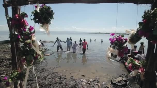 KENIA, KISUMU - 20 DE MAYO DE 2017: Los africanos salen del agua en la orilla del lago en un día soleado de verano . — Vídeo de stock