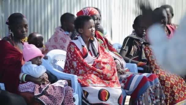 KENIA, KISUMU - 20 DE MAYO DE 2017: Mujeres africanas vestidas con ropas nacionales brillantes de la tribu maasai sentadas en sillas . — Vídeos de Stock