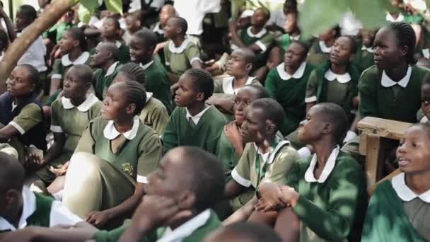 KENIA, KISUMU - 20 DE MAYO DE 2017: Un gran grupo de niños africanos en uniforme sentados en el suelo afuera, cerca de la escuela . — Vídeo de stock