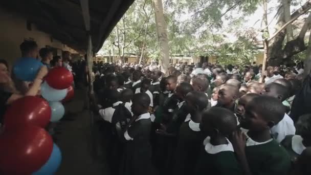 Kenya, Kisumu - 2017. május 20.: Kaukázusi önkéntesek nagy csoportja afrikai gyermekek lufi, tánc. — Stock videók