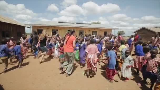 KENYA, KISUMU - MAY 20, 2017: Caucasian women dancing with African children outside the school building. — Stock Video