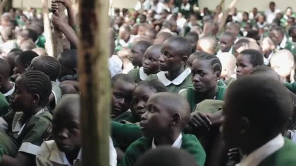 アフリカの男の子と女の子の学校外の生徒の大群衆の中に座っているのケニアのキスム - 2017 年 5 月 20 日: クローズ アップ ビュー. — ストック動画