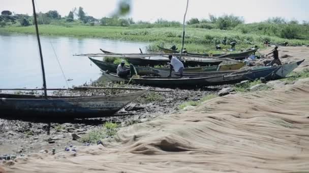 KENIA, KISUMU - 20 DE MAYO DE 2017: Pescadores sentados en barcos en la orilla del mar en África, preparándose para la jornada laboral . — Vídeos de Stock
