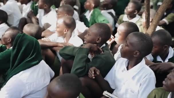 Keňa, Kisumu - 20 května 2017: Skupina afrických dětí v zelené uniformě sedí na zemi, nedaleko školy. — Stock video