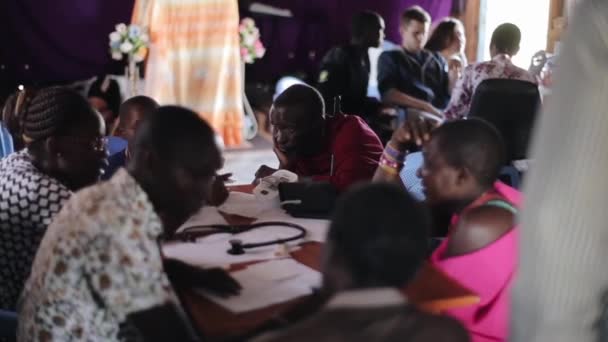 Kenya, kisumu - 20. Mai 2017: Gruppe afrikanischer Menschen sitzt drinnen, am Tisch und spricht mit Ärzten. — Stockvideo