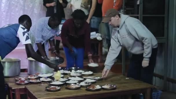 KENYA, KISUMU - MAY 20, 2017: Group of African teenagers putting rise in plates, preparing dinner together. — Stock Video