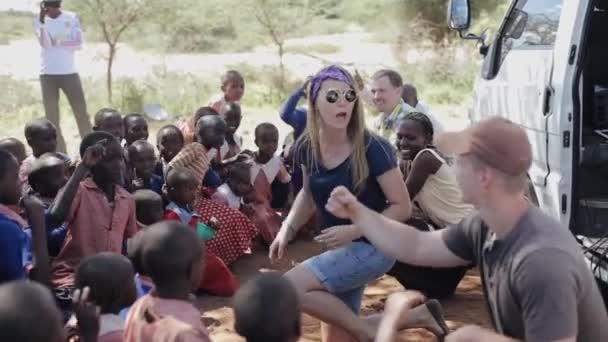 KENYA, KISUMU - MAY 20, 2017: Happy caucasian woman and man show movement, dance with African children. — Stock Video