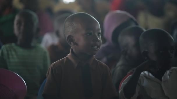 KENIA, KISUMU - 20 DE MAYO DE 2017: Retrato de un niño africano feliz sentado dentro con un grupo de niños y bailando, sonriendo . — Vídeos de Stock