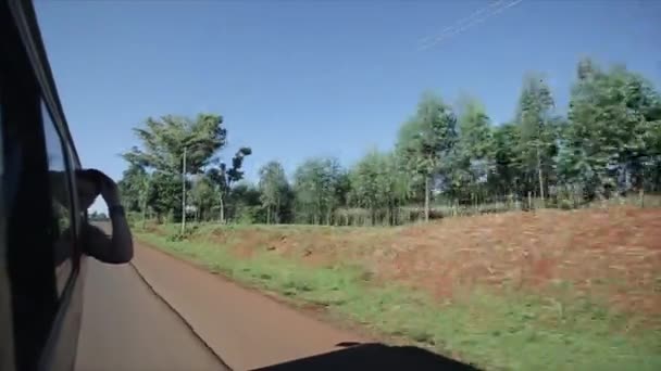 Kenia, Kisumu - 20 mei 2017: Uitzicht vanaf binnen een rijdende auto, mensen zitten in busje met geopende vensters. Auto rijdt door de land weg zonnige dag in Afrika. — Stockvideo