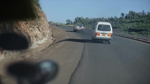 KENIA, KISUMU - 20 DE MAYO DE 2017: Vista desde el interior de un automóvil en movimiento. El automóvil está montando a través de la carretera del campo, se enciende la serpentina en el día soleado brillante en África . — Vídeo de stock