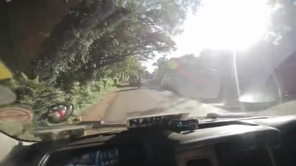 Keňa, Kisumu - 20 května 2017: Výhled přes čelní sklo z uvnitř auta. Auto je jízda městem v Africe v jasný slunečný den. — Stock video