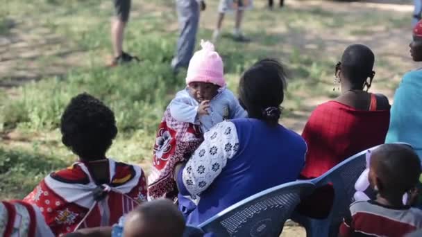 Kenya, kisumu - 20. Mai 2017: Frauen mit Kindern eines lokalen afrikanischen Stammes, Massai auf Stühlen sitzend. — Stockvideo