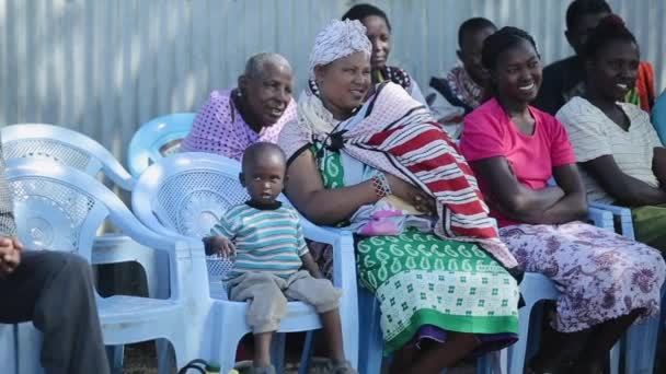 KENIA, KISUMU - 20 DE MAYO DE 2017: Mujeres jóvenes africanas con niños de la tribu maasai local sentadas en sillas . — Vídeos de Stock