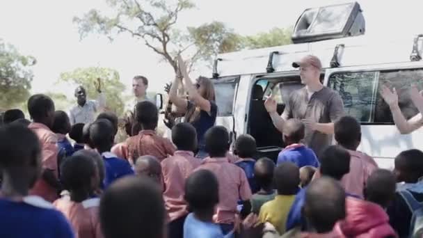 KENYA, KISUMU - MAY 20, 2017:Caucasian volunteers dancing with African pupils, children outside the school. — Stock Video