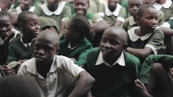 KENYA, KISUMU - MAY 20, 2017:group of African children in green uniform sitting on ground, smiling, talking. — Stock Video