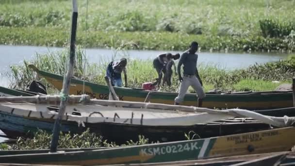 KENIA, KISUMU - 20 DE MAYO DE 2017: Joven africano preparando su barco antes del trabajo. Gente duchándose en el lago . — Vídeos de Stock