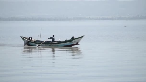 Pescatore africano sta passando vicino alla riva in barca e canottaggio da solo nel mare . — Video Stock