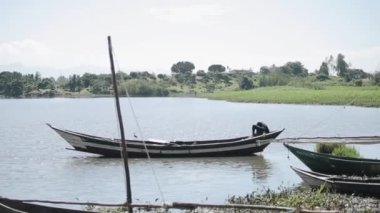 Yalnız deniz kıyısında iskeleye kürek tekne içinde oturan genç Afrika adam.