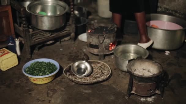 KENIA, KISUMU - 20 DE MAYO DE 2017: Vista de cerca de la joven africana preparando la cena, hierve agua sobre carbones quemados para su familia en un patio trasero . — Vídeo de stock
