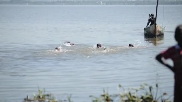 Grupo de niños africanos, niños nadan en el lago, flotan detrás del barco . — Vídeo de stock
