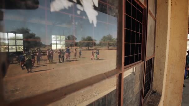 Spiegelung im Fenster. Afrikanische Kinder spielen auf dem Fußballplatz. — Stockvideo