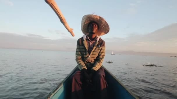 Pescador sério em um chapéu de palha senta-se no barco. Homem vai para o mar na África ao amanhecer da manhã . — Vídeo de Stock