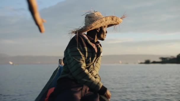 Giovane africano in paglia cappello si siede in barca a motore all'alba e guardare barche a vela in mare . — Video Stock