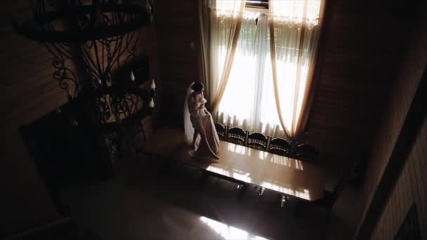 Вид зверху на красиву наречену, що йде уздовж столу босоніж, в шовкових піжамах, і вуалі, тримаючи її весільну сукню — стокове відео