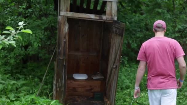 Ein Mann schüttet Wasser aus einem Eimer auf einer Dorftoilette. nach dem Brand. Ein Feuer stoppen — Stockvideo