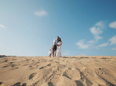 Beyaz aile beyaz giysili bebekle portresi sands kumul üzerinde bekliyoruz. Hamile mpther. Yeni doğan
